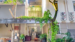 A multi-level building with a covered outdoor seating area, potted plants, and a staircase leading to an interior space. - Luxury Deluxe DBL Retreat W/ Free Wifi and Parking (Jakarta)