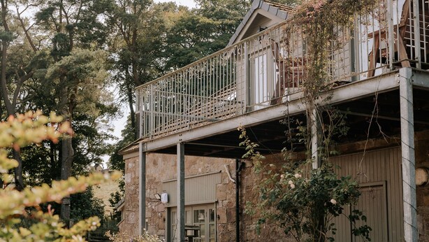 A rustic building with a balcony, stone walls, and potted plants. - The Keep -  A Stunning One Bedroom Apartment (Kirknewton)