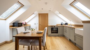 A modern kitchen with skylights, a dining area, and a built-in oven. - The Keep -  A Stunning One Bedroom Apartment (Kirknewton)