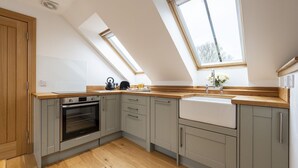 A modern kitchen with a skylight, built-in oven, and a large window. - The Keep -  A Stunning One Bedroom Apartment (Kirknewton)
