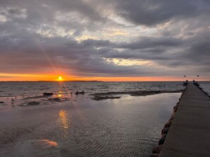 Ein Sonnenuntergang über dem Meer mit einem Steg, der sich ins Wasser erstreckt.