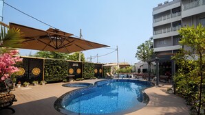 A swimming pool with a tiled edge, surrounded by a wooden deck and potted plants.