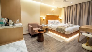 A hotel room with a bed, bedside table, chair, and a desk with a chair.