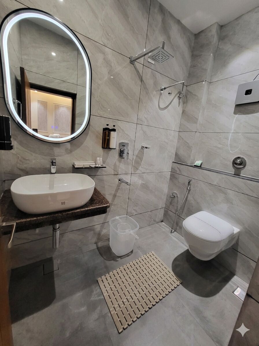 A modern bathroom with a round mirror, a white sink, a toilet, and a shower area.