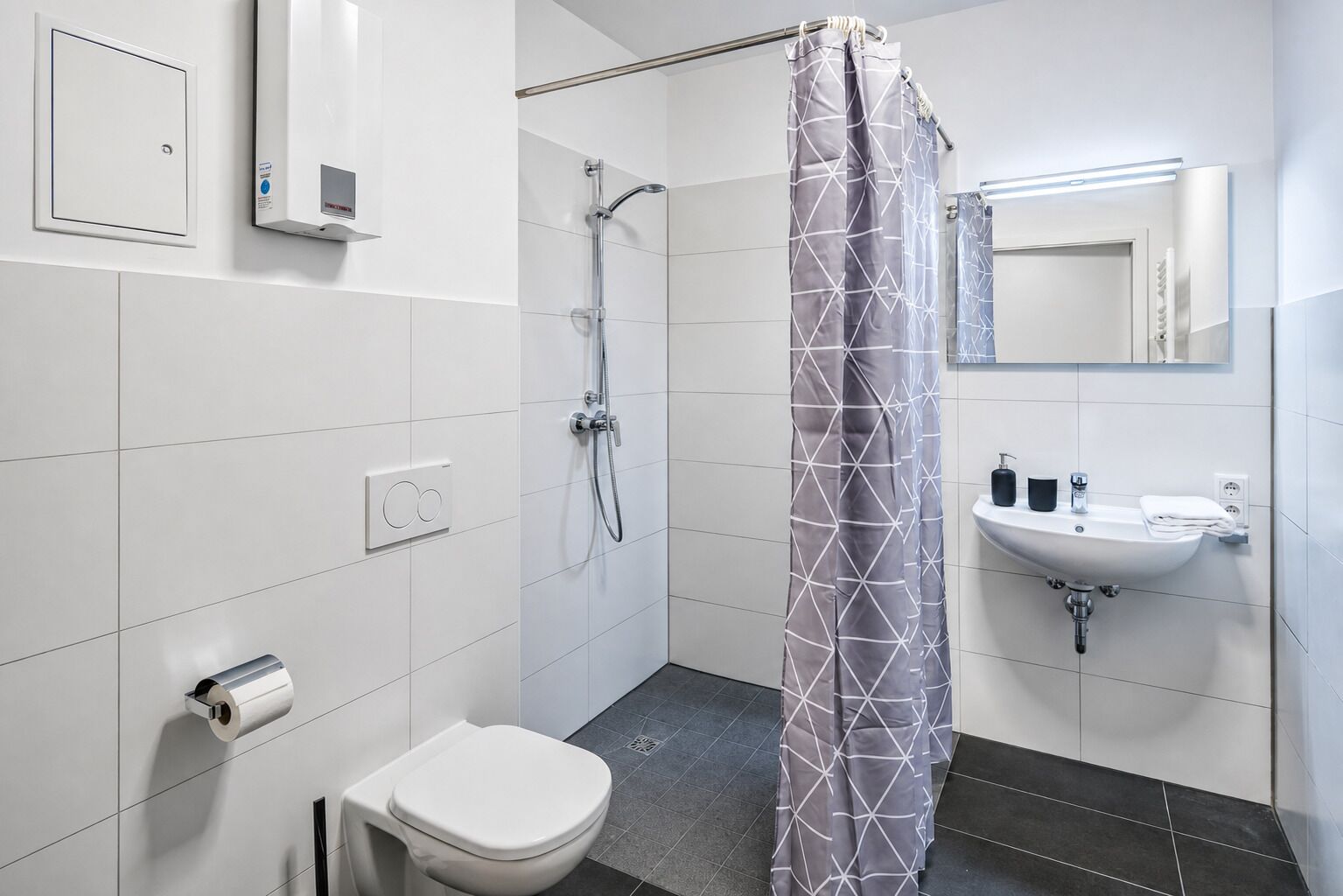 A modern bathroom with a toilet, shower, and sink.
