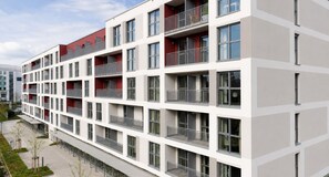 Un edificio residencial de varios pisos con balcones, fachada plana y cielo despejado.