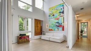 Ein großzügiger Wohnbereich mit einem weißen Sofa, einem Holzkasten und großen Fenstern.