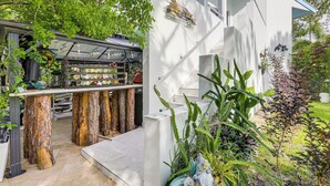 Ein modernes Haus mit einem einzigartigen Küchendesign, das Baumstamm-Hocker, eine Bar mit Glastür und eine Treppe zu einer oberen Ebene zeigt.