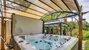 Ein Whirlpool unter einem Baldachin, umgeben von viel Grün.
