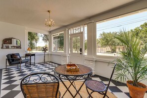 A room with a checkered floor, a round table with a basket, wicker chairs, a potted plant, a chandelier, and a door leading outside. - 2-Unit Bundle in Eustis: Walk to Ferran Park! (Eustis)