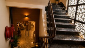A modern staircase with a glass door leading to a room with a sofa and a coffee table. - Qotel Comfort Oasis Rajouri Garden (New Delhi)