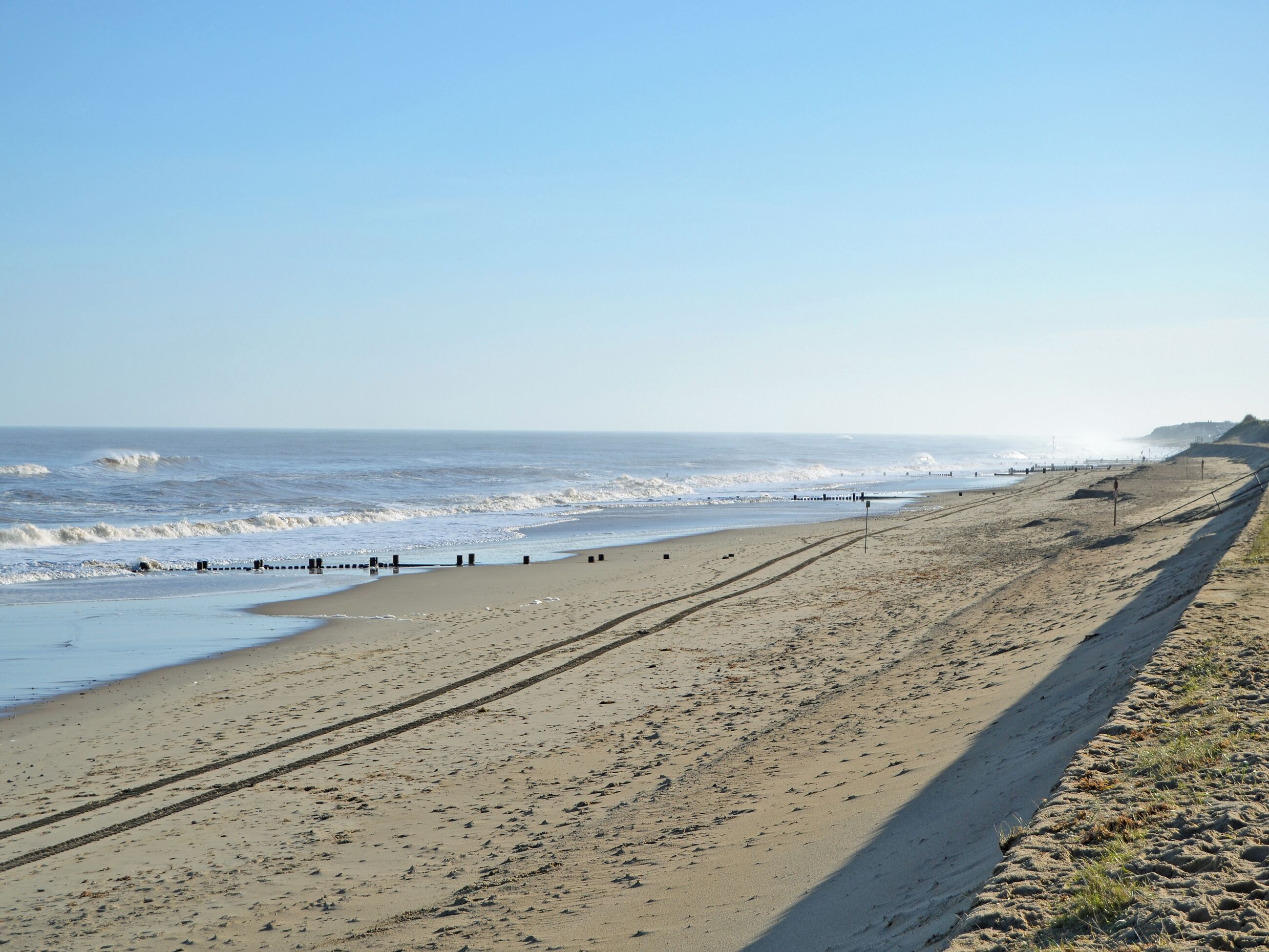 Een strand met heldere lucht, golven en een zandstrand.