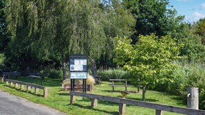 Ein Park mit einem Hinweisschild, Bänken und einem Holzzaun.