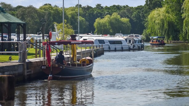 Ein Kanal mit vertäuten Booten, einem Gebäude mit Gründach und einer Statue.
