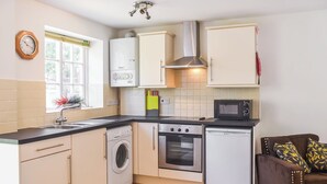 Eine kompakte Küche mit Waschmaschine, Backofen, Mikrowelle und kleinem Kühlschrank.