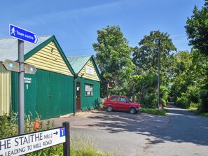 Ein grünes Gebäude mit einem Schild für die Alte Yachthafenstation und einem roten Auto davor geparkt.