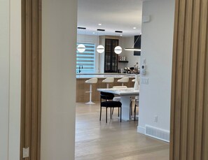 Cozinha moderna com área de refeições, piso de madeira e iluminação pendente.
