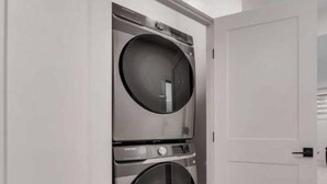 A laundry room with two stacked front-loading washing machines. - Pavilion Lakefront Luxe 3 Bdrm near Lake! (Chestermere)