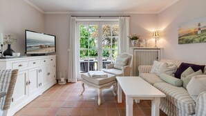 Una sala acogedora con televisor, un sofá, una mesa de comedor y una silla.