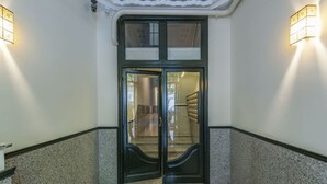 A hallway with a double door, a doormat, and two wall-mounted light fixtures. - Zurbano Pad Near Castellana (Madrid)
