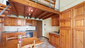 Une cuisine avec des meubles en bois, une table à manger et un escalier menant à l’étage supérieur.