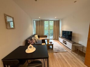 Ein modernes Wohnzimmer mit einer Couch, einem Esstisch und einem Fernseher.