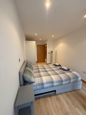 Un dormitorio con cama, mesita de noche, armario y espejo.