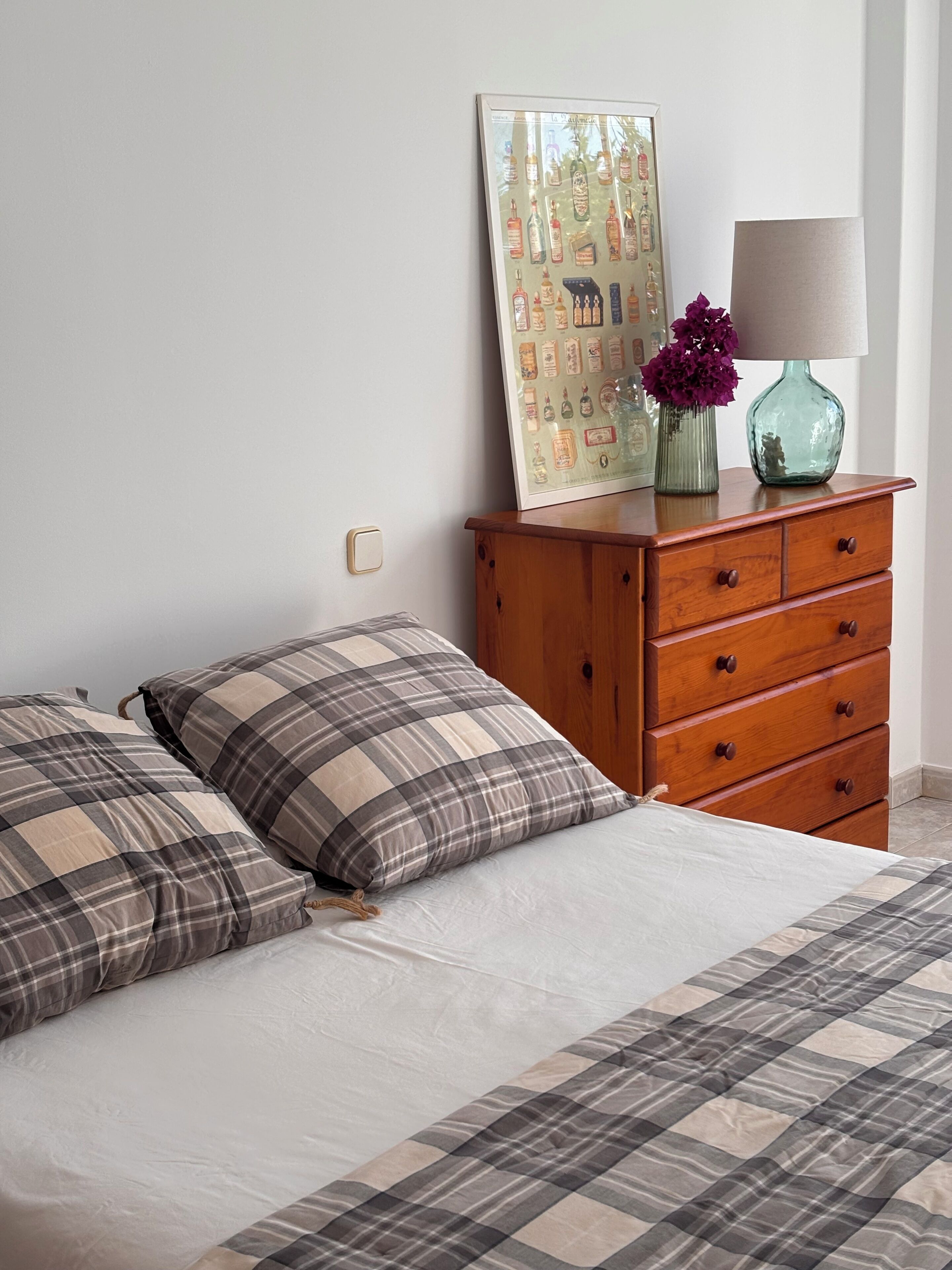 A bedroom with a bed, a dresser, a mirror, and a wall art piece.