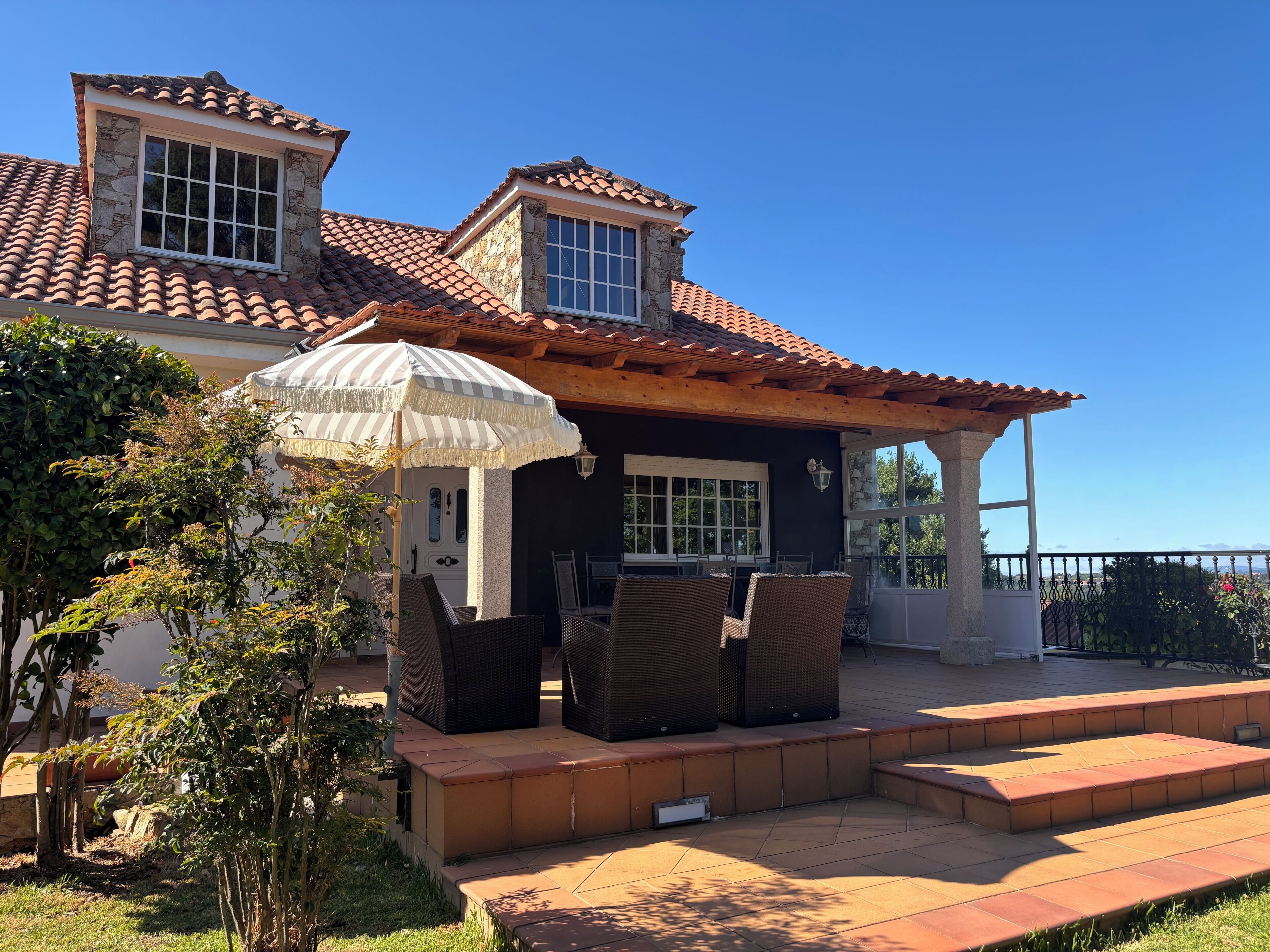 A house with a patio area, outdoor furniture, and a view of the ocean.