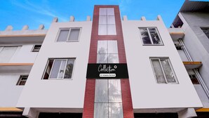 A modern building with a central vertical red and white panel, multiple windows, and a sign reading 'Collection Company Serviced'. - Super Deluxe Room Kris Resort (Calangute)
