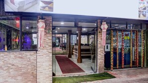 A hotel entrance with a glass door, a red carpet, and a brick facade. - Super Deluxe Room Kris Resort (Calangute)