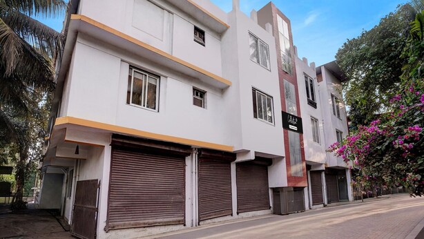 A multi-story building with closed shutters, a visible sign, and a clear sky. - Super Deluxe Room Kris Resort (Calangute)