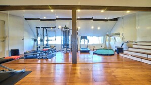 Un gimnasio con equipamiento de ejercicio, suelos de madera y ventanas amplias.