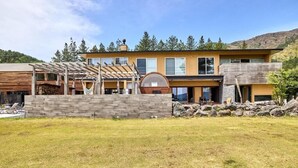A modern two-story house with a stone facade, a covered patio, and a large circular window. - Oku Fuji Lakeside (kawaguchiko Town, Minamitsuru-gun)