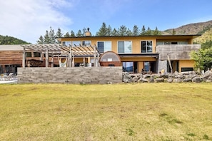 A modern two-story house with a stone facade, a covered patio, and a large circular window.