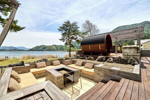 A wooden deck with a built-in seating area and a fire pit, overlooking a lake and hills. - Oku Fuji Lakeside (kawaguchiko Town, Minamitsuru-gun)