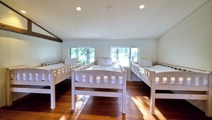 A room with three wooden beds arranged in a row, a sloped ceiling, and large windows allowing natural light. - Oku Fuji Lakeside (kawaguchiko Town, Minamitsuru-gun)