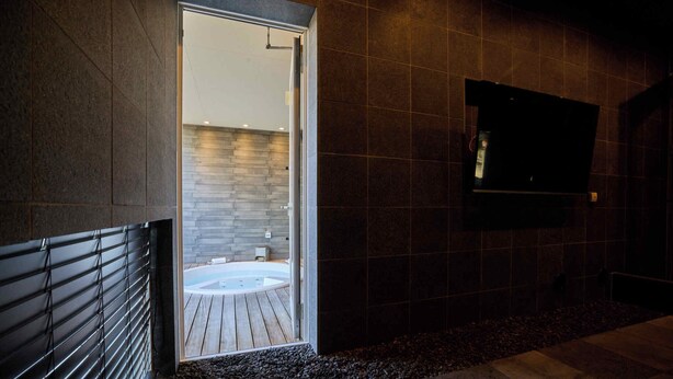 Un baño moderno con pared de piedra, suelo de madera y bañera.