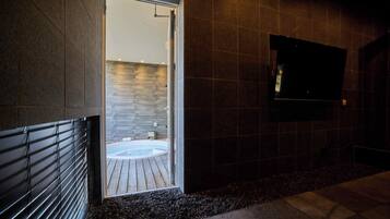 Un bagno moderno con una parete in pietra, un pavimento in legno e una vasca da bagno.