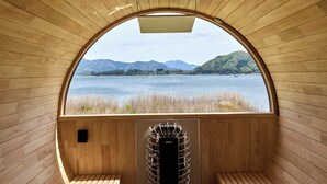 Una cabaña de madera con un amplio ventanal de arco que da a un lago y montañas.