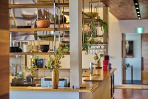 Una cocina moderna con estantes de madera, un jarrón con flores y una pequeña figurita.