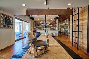 Un interior moderno con piso de madera, un área de estar central con una mesa redonda y un ventanal que ofrece vistas.