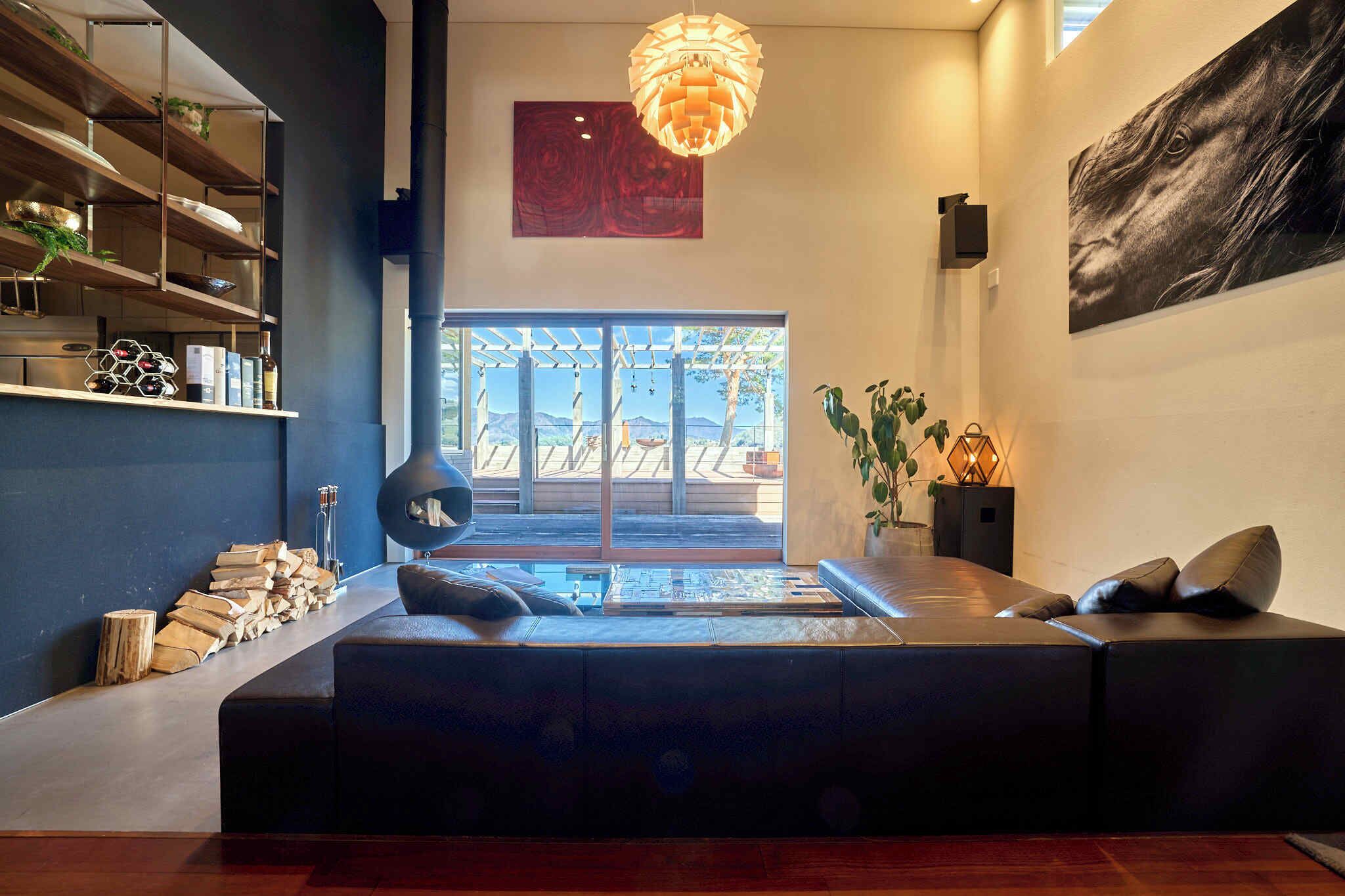 Uma sala de estar moderna com um sofá seccional, lareira, uma janela grande com vista e um lustre.