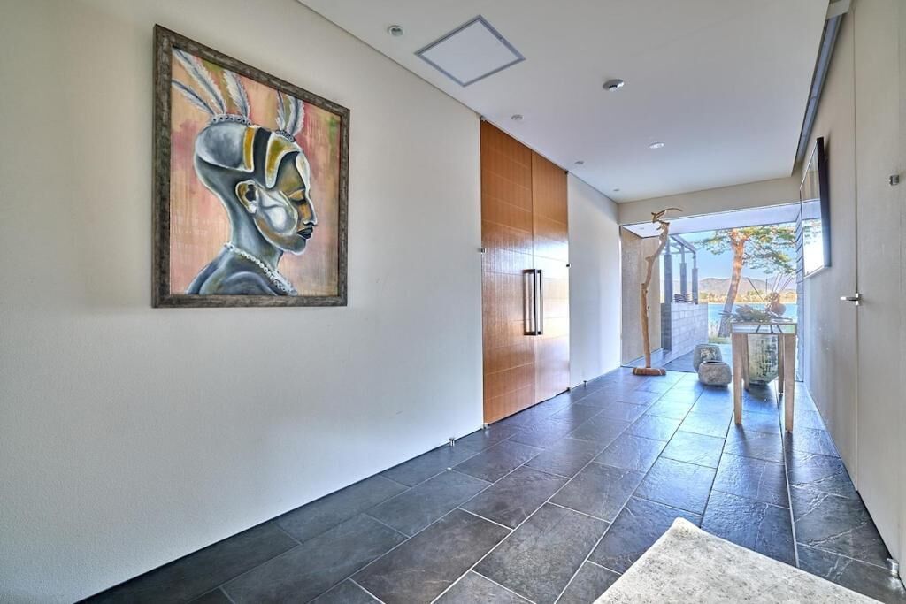 A modern hallway with a large abstract painting, a wooden door, and a view of the outdoors.
