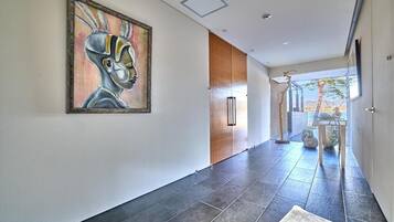 A modern hallway with a large abstract painting, a wooden door, and a view of the outdoors.