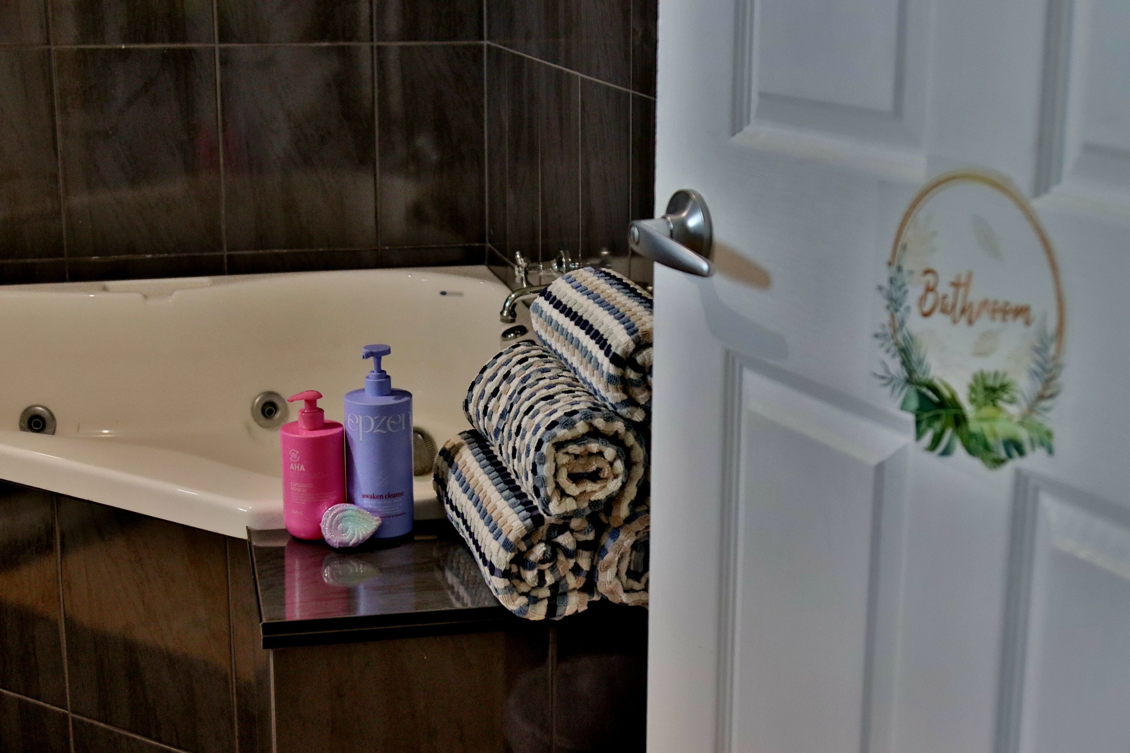 A bathroom with a bathtub, a towel rack with rolled towels, and toiletries on the counter.