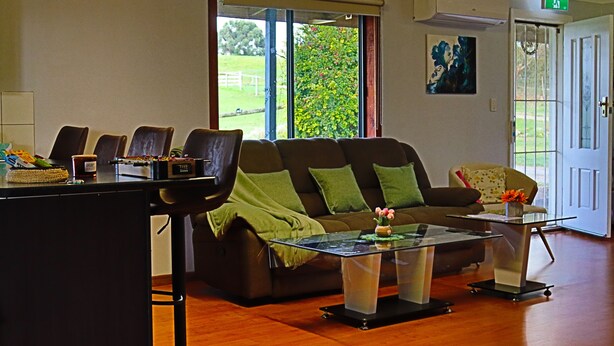 Ein Wohnzimmer mit einer Couch, Sesseln, einem Couchtisch und einer Tür, die nach draußen führt.
