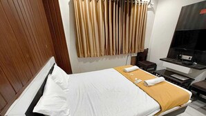 Una habitación de hotel con una cama, televisión, escritorio y una silla.