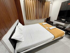 A hotel room with a bed, a TV, a desk, and a chair.