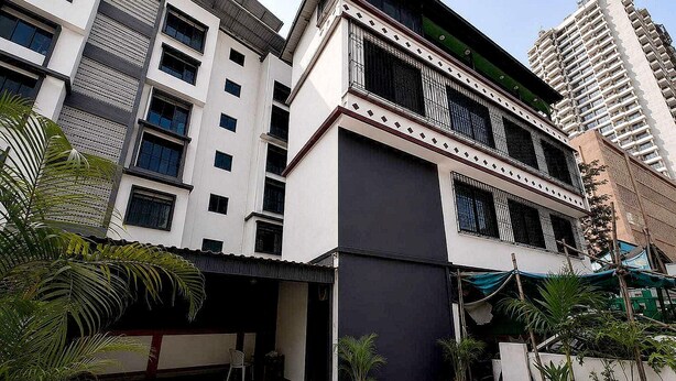 Un edificio de varios pisos con fachada plana, ventanas grandes y una entrada protegida por una reja.